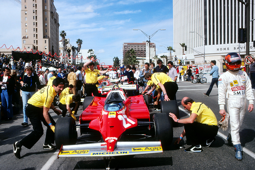 Gilles Villeneuve walks away from his Ferrari 126CK that is being serviced by his mechanics.