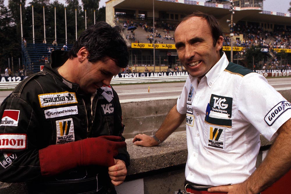 Second place finisher Alan Jones gingerly removes his driving glove following an altercation at Chiswick High Road that left him with a broken finger. With him is Williams team manager Frank Williams.