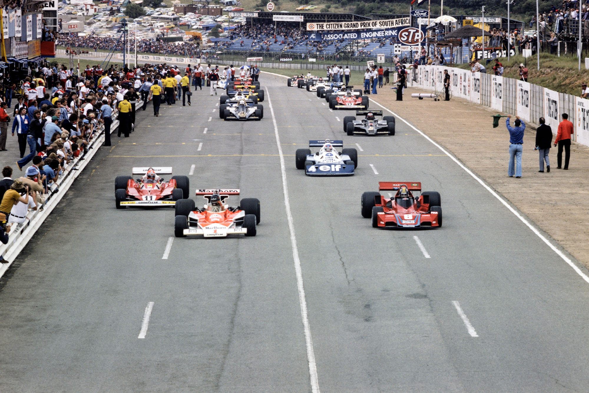 James Hunt (McLaren) and Carlos Pace (Brabham) contest the lead down to the first corner at the 1977 South African Grand Prix, Kyalami.