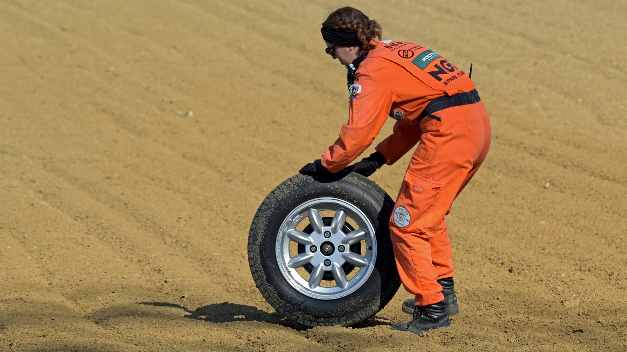 TVR wheel is rolled through Brands Hatch gravel by a marshal