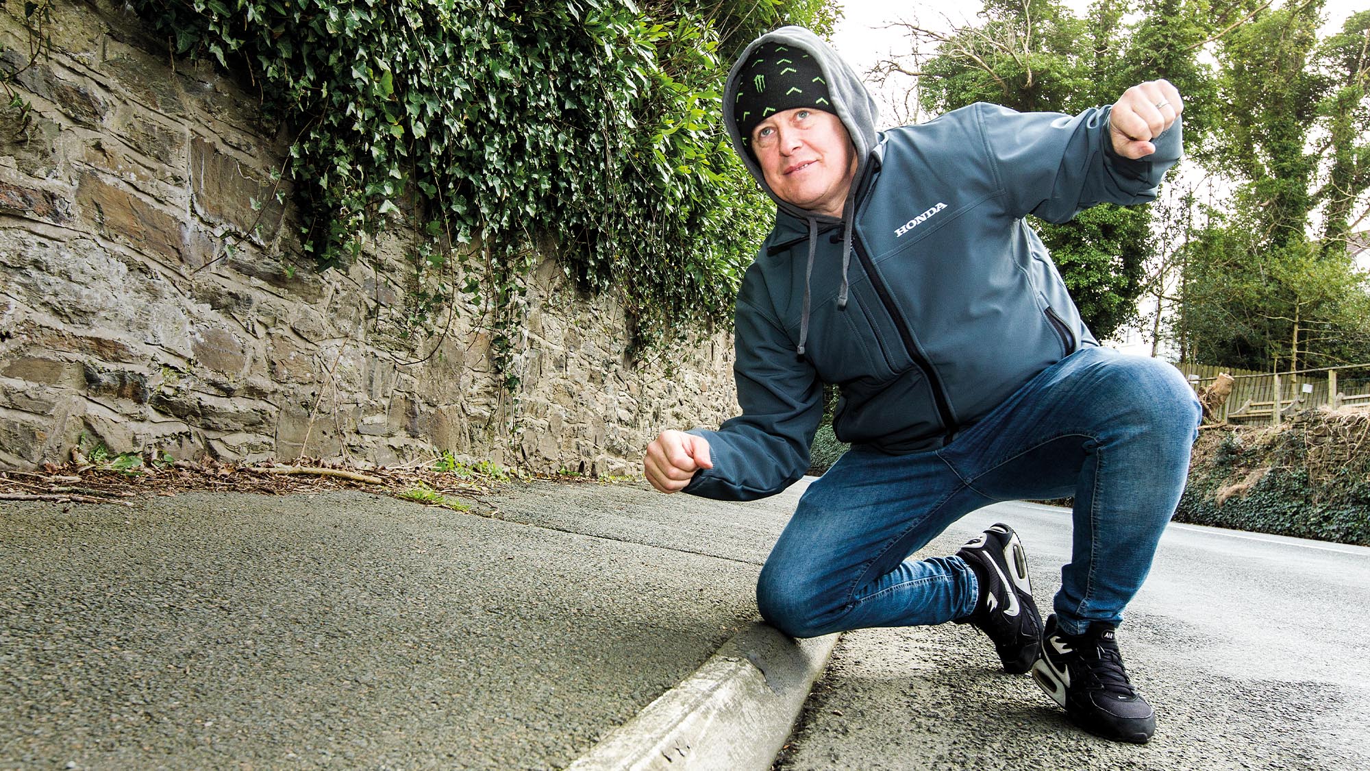 John McGuinness kneels down on the kerb to demonstrate Isle of Man TT cornering technique